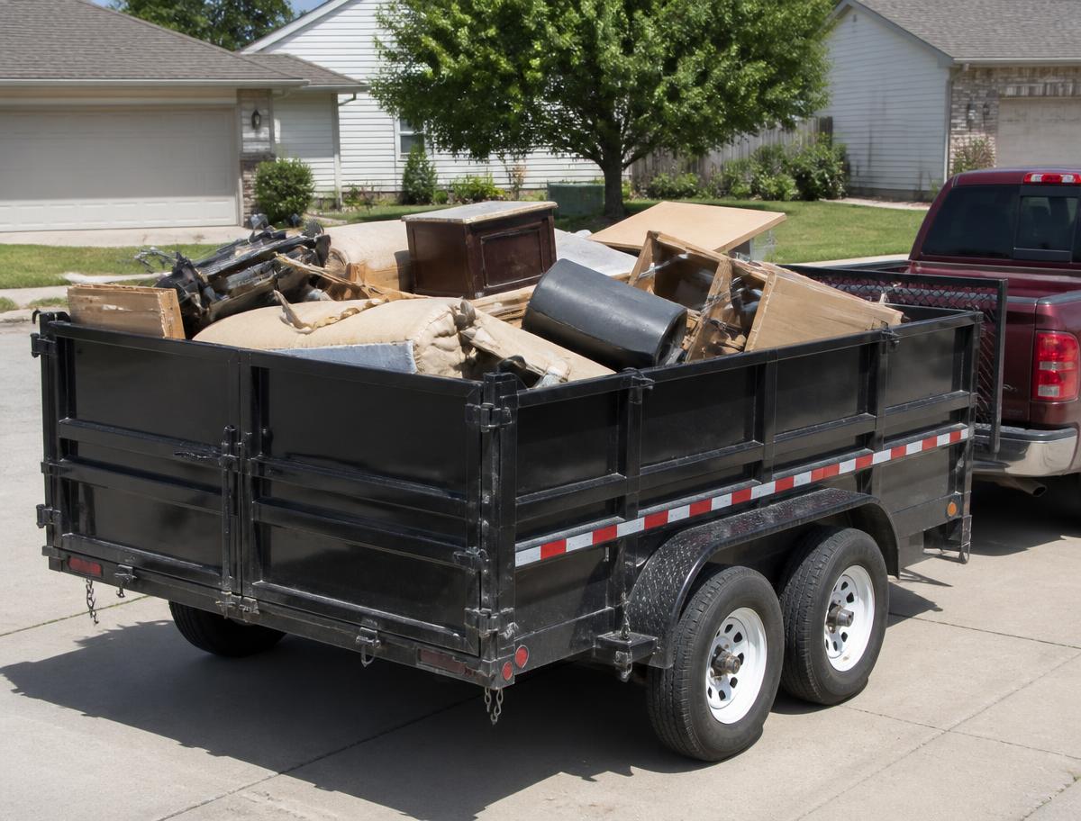 Dump trailer loaded with household furniture and junk in a driveway